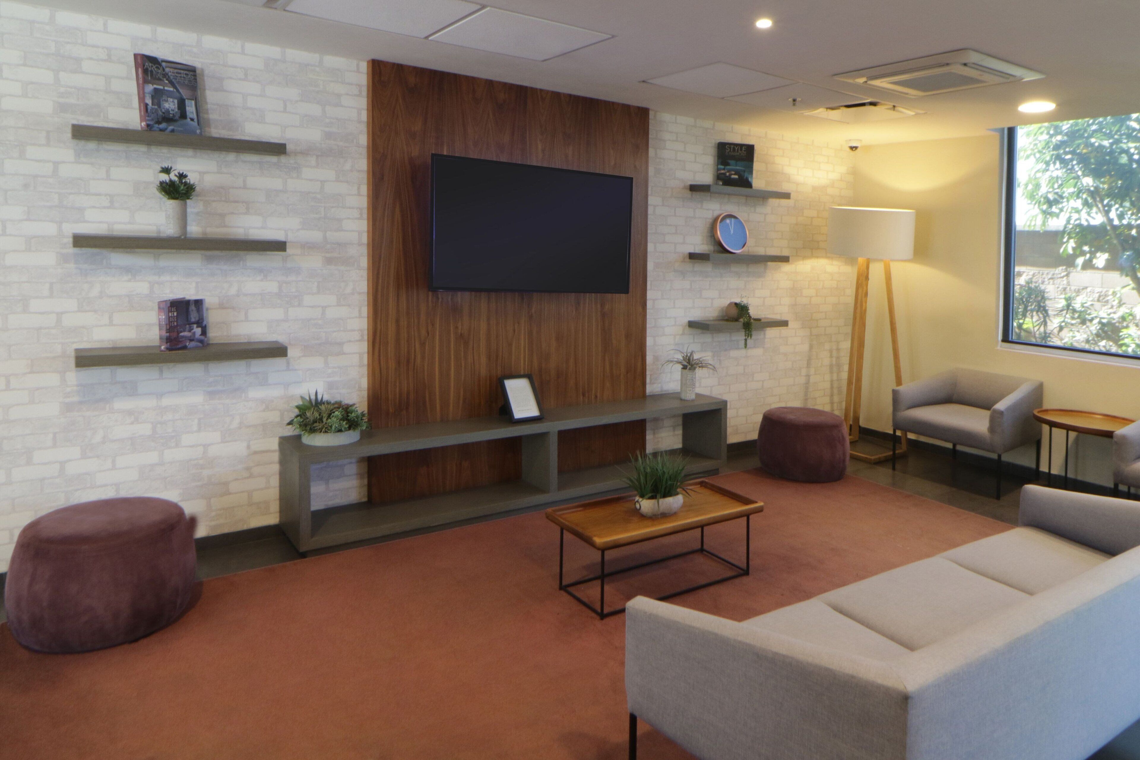 A modern living room with a flat-screen TV, a sofa, a coffee table, and a lamp.