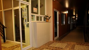 A hotel corridor with a tiled floor, a door with a sign, and a window with a flower vase. - Won DD Place (Roi Et)