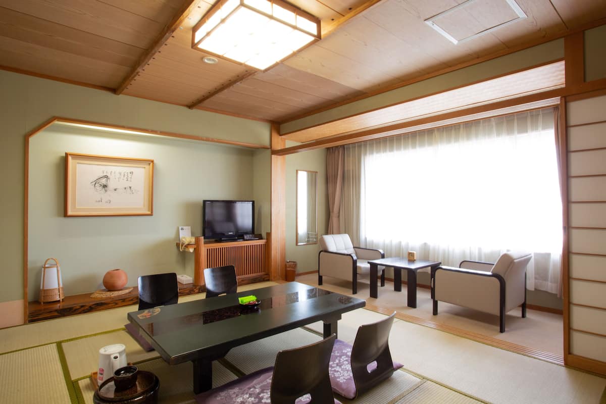 Un salon de style japonais traditionnel, avec un sol recouvert de tatamis, une table basse et un téléviseur.