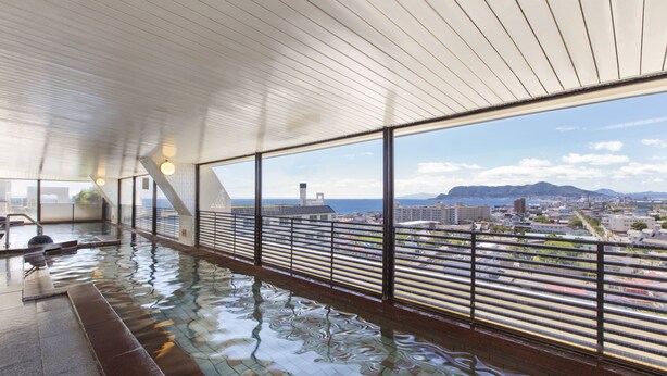 Une piscine intérieure moderne avec vue sur la ville, de grandes fenêtres et un plafond en bois.