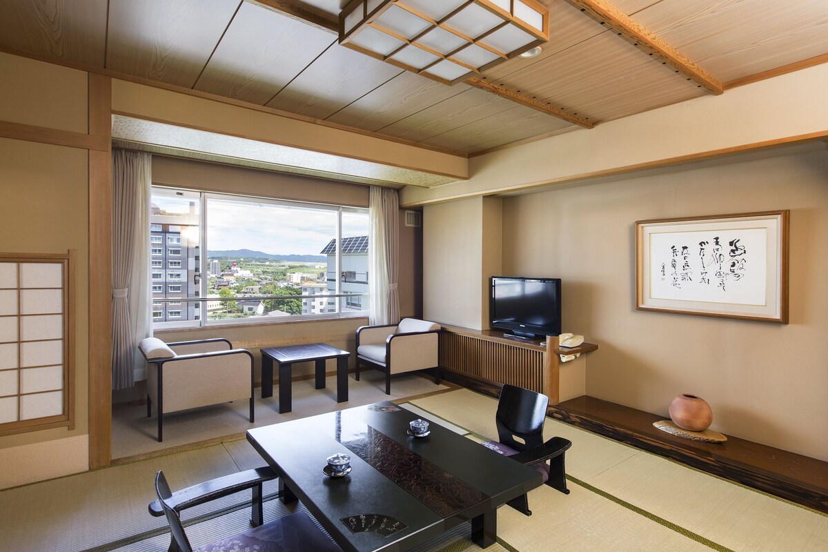 A traditional Japanese-style room with tatami flooring, a low table, and a television.