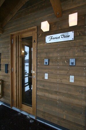 A wooden cabin with a sign reading "Forest View." There are four light switches on the wall, and a door labeled with the letter "A."