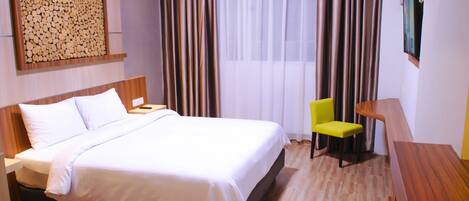 A hotel room with a large bed, a wooden headboard, a desk with a chair, and a painting on the wall.