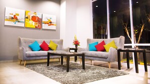 Una sala de estar moderna con dos sofás, cojines de colores, una mesa de centro y arte abstracto en la pared.