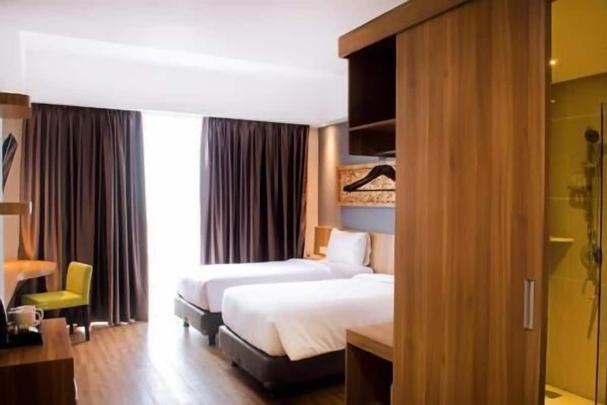 Ein Hotelzimmer mit zwei Betten, einem Schreibtisch mit Stuhl, einem Kleiderschrank und einer Dusche.