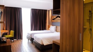 Habitación de hotel con dos camas, un escritorio, una silla y zona de ducha.