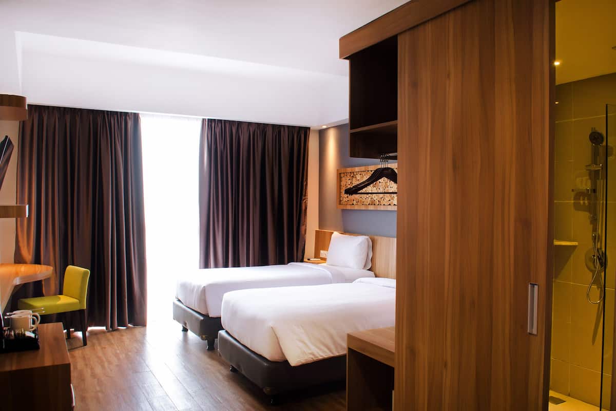 Ein Hotelzimmer mit zwei Betten, einem Schreibtisch, einem Stuhl und einer Dusche.