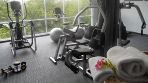 Un gimnasio con máquinas de cardio, equipo de levantamiento de pesas y mancuernas.