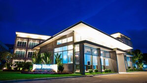 Un hotel moderno con una amplia fachada de vidrio, una entrada bien iluminada y un letrero con el nombre.