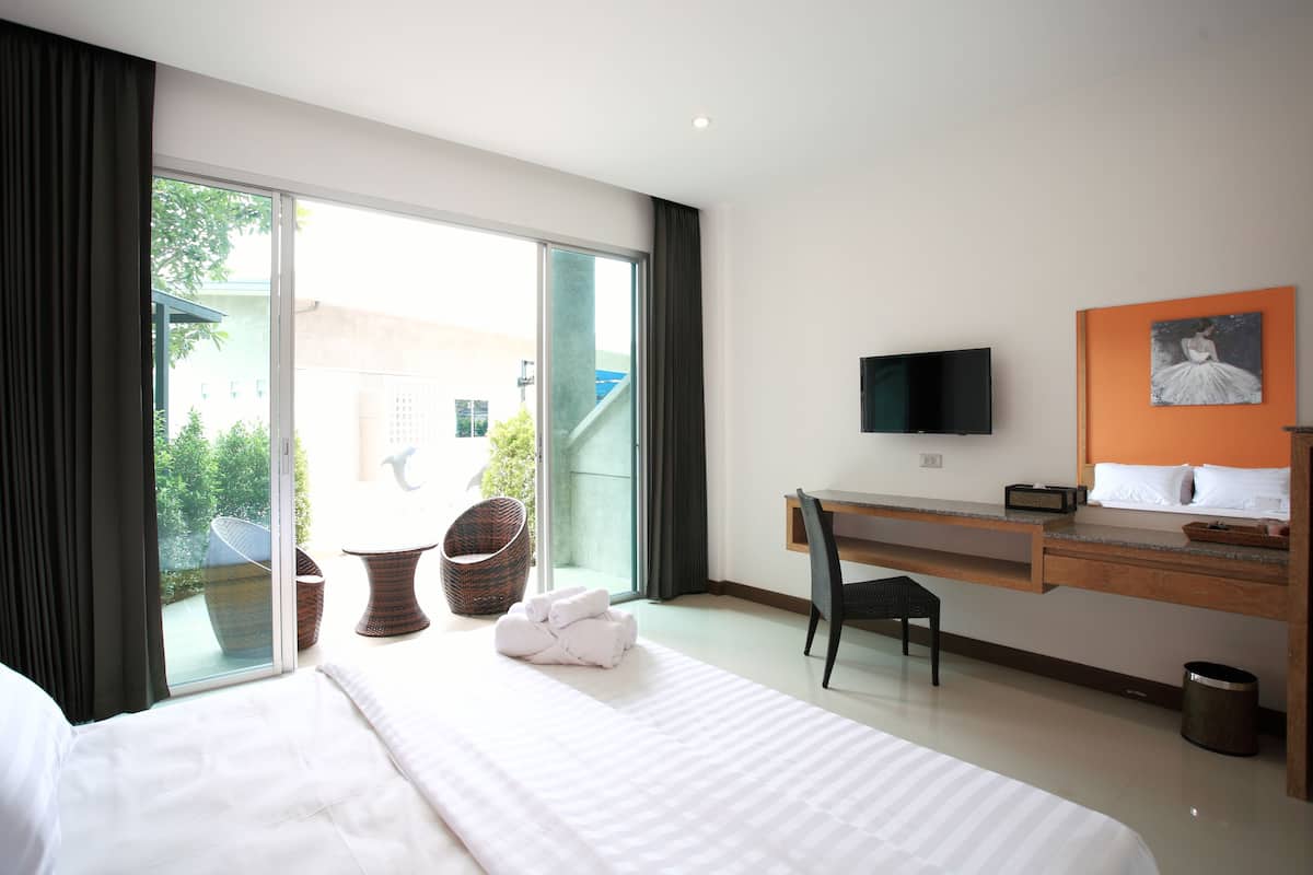 A hotel room with a bed, a desk, a chair, a television, and a view of the outdoors.