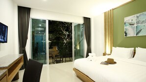 Una habitación de hotel con cama, escritorio, silla, zona de comedor con mesa y sillas, y puerta corrediza de vidrio que da a un área exterior.