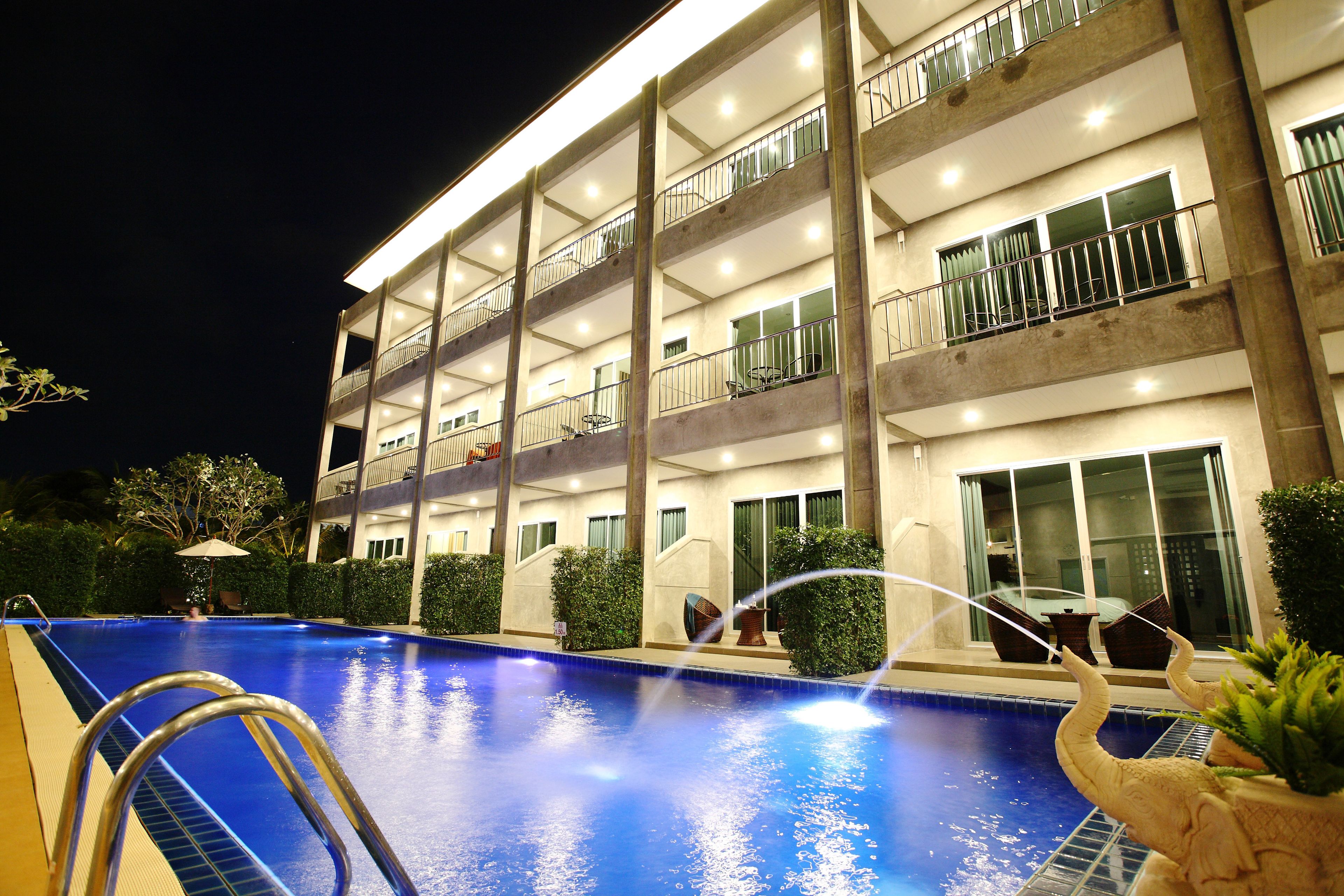 Ein mehrstöckiges Hotel mit Schwimmbad, Balkonen und einer gut beleuchteten Fassade.