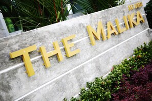 A sign with the text "THE MALIKA" in large yellow letters on a grey background. - The Malika (Phuket)