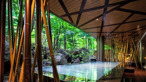 A modern interior with a glass pool reflecting the surrounding bamboo forest.