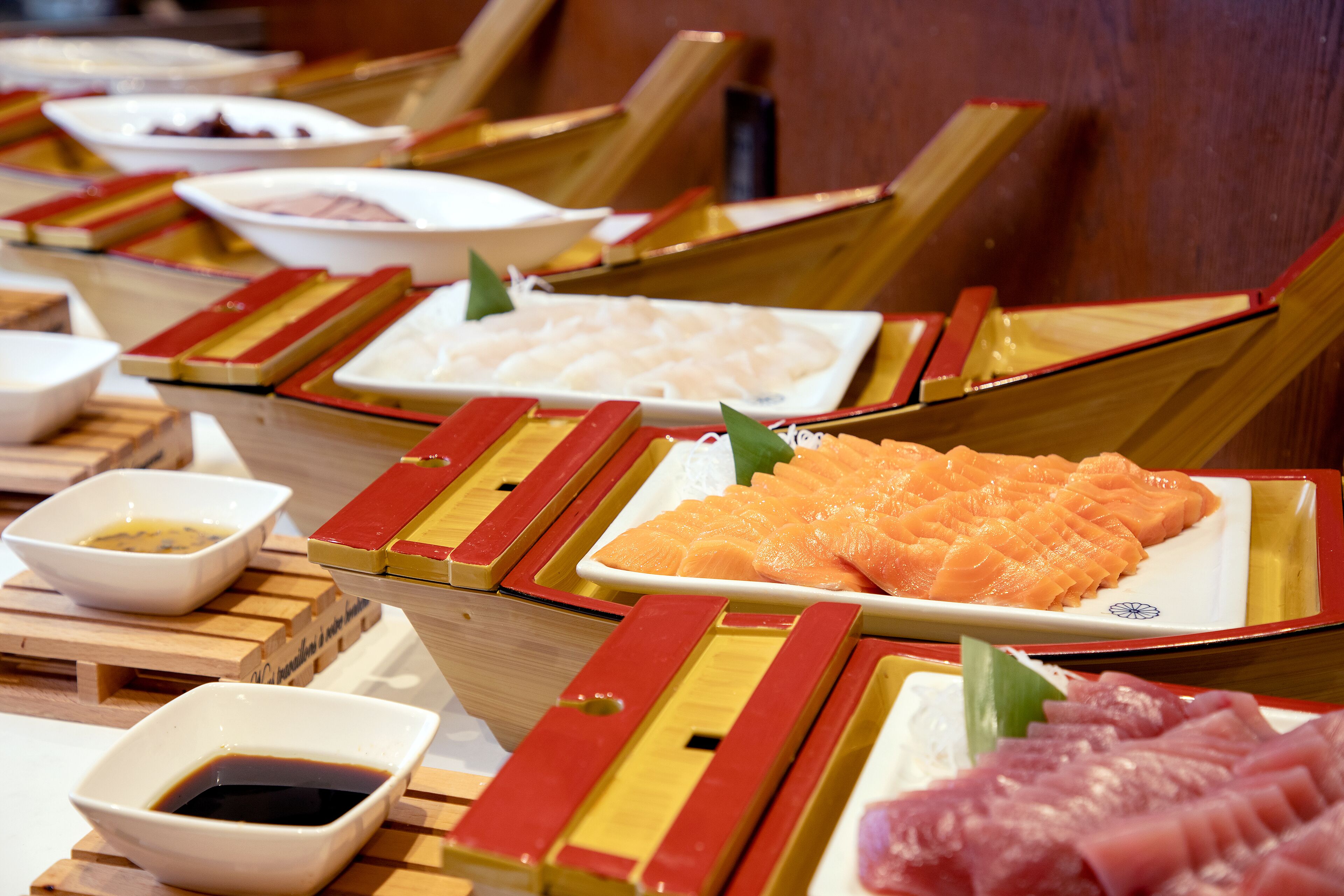 Un bar de sushi con diferentes tipos de sushi expuestos en bandejas de madera.