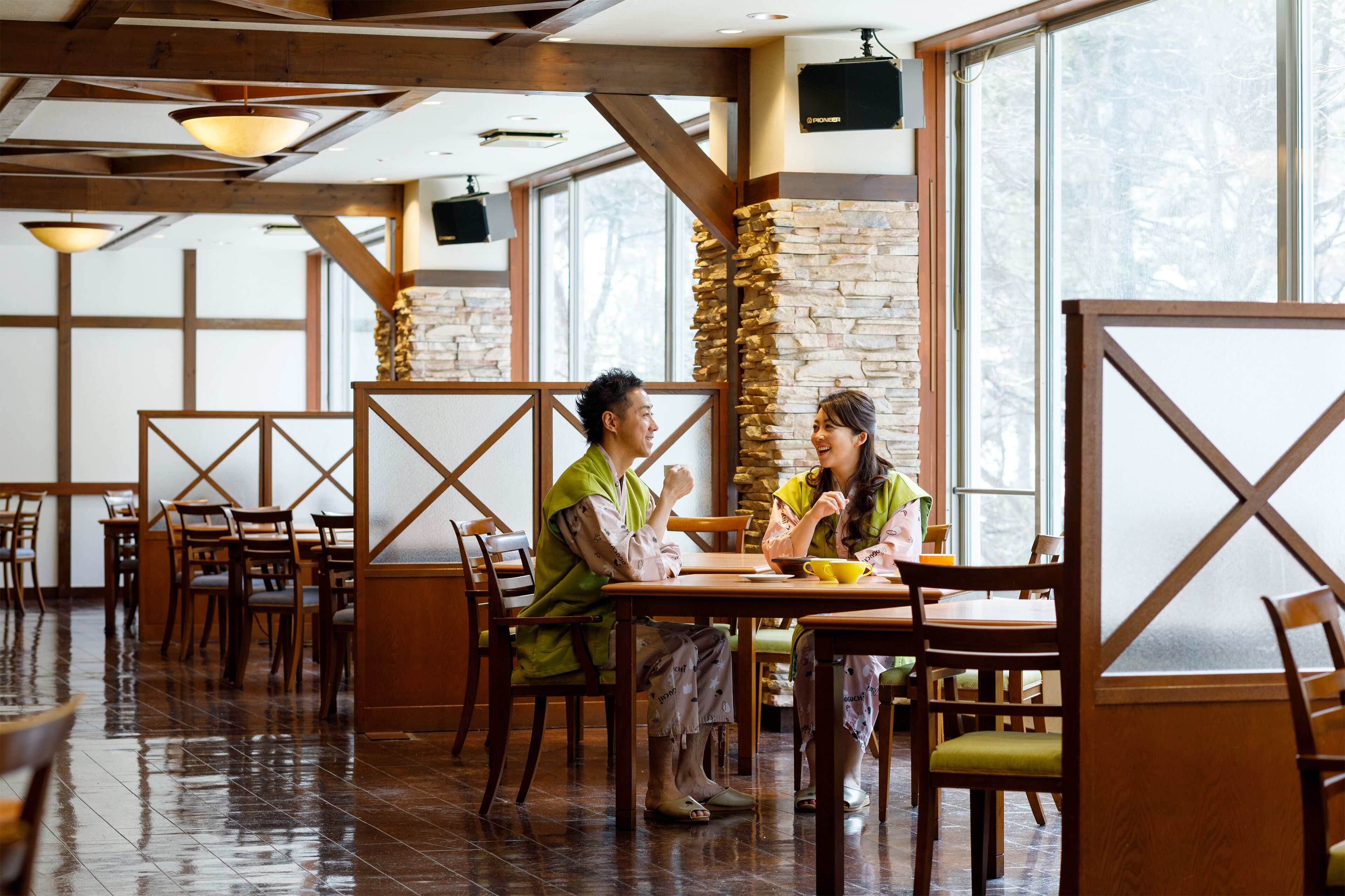 Um restaurante com mobiliário de madeira, paredes de pedra e grandes janelas.