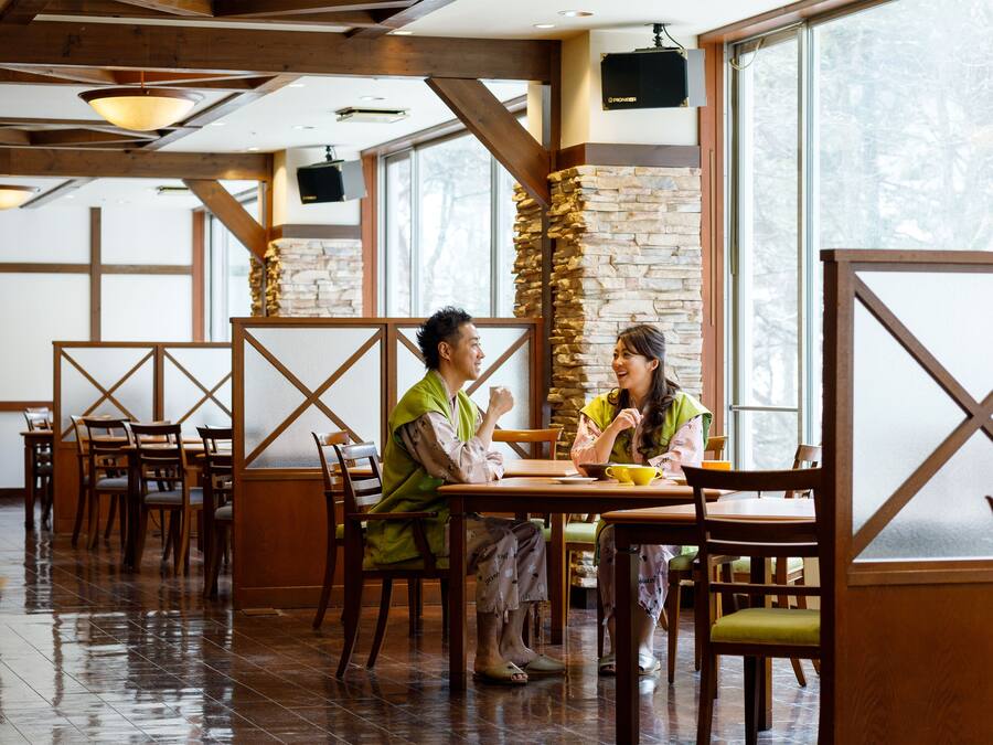 Um restaurante com mobiliário de madeira, paredes de pedra e grandes janelas.