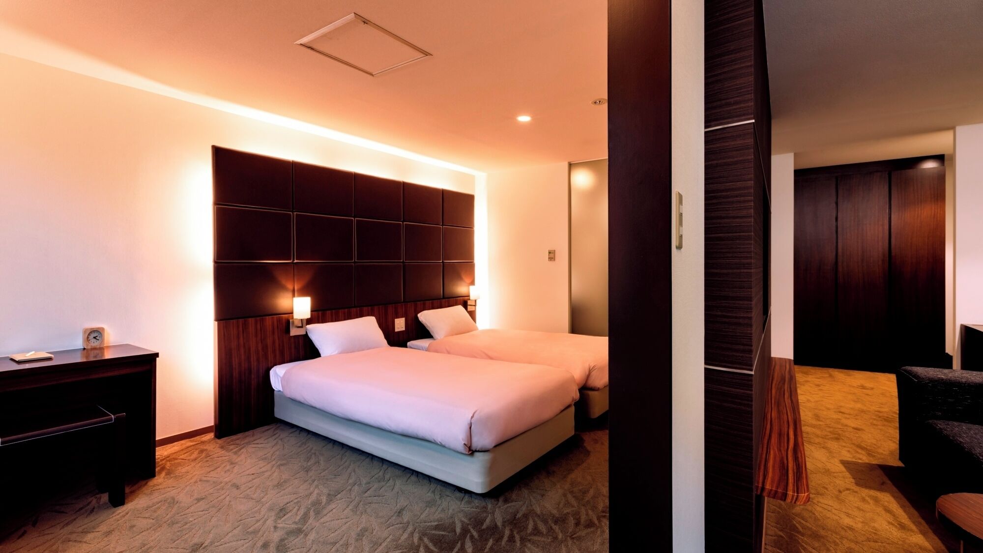 Une chambre d’hôtel avec un grand lit, des tables de chevet, un bureau et une armoire.
