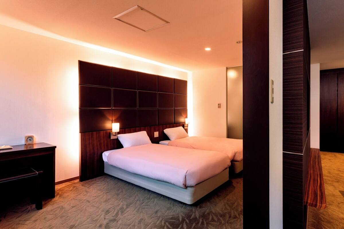 Ein Hotelzimmer mit einem großen Bett, Nachttischen, einem Schreibtisch und einem Kleiderschrank.
