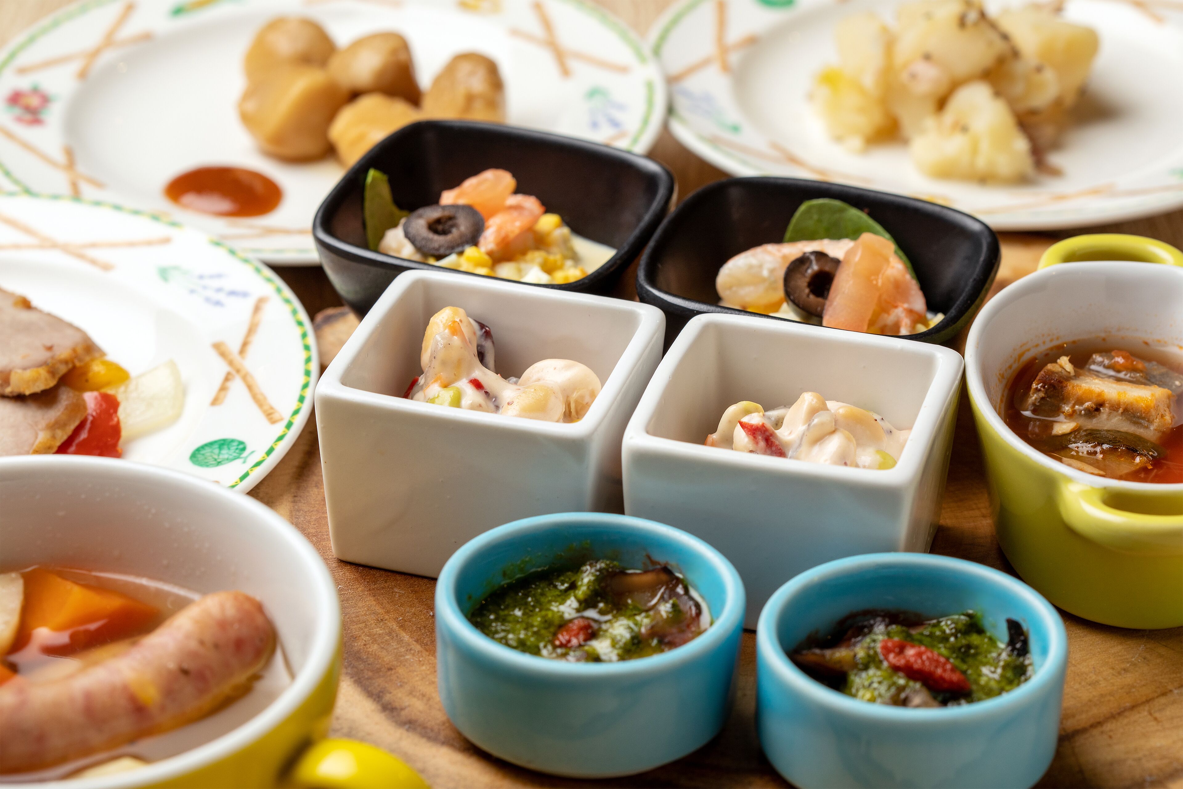 Una variedad de platos en recipientes pequeños, incluyendo mariscos y verduras.