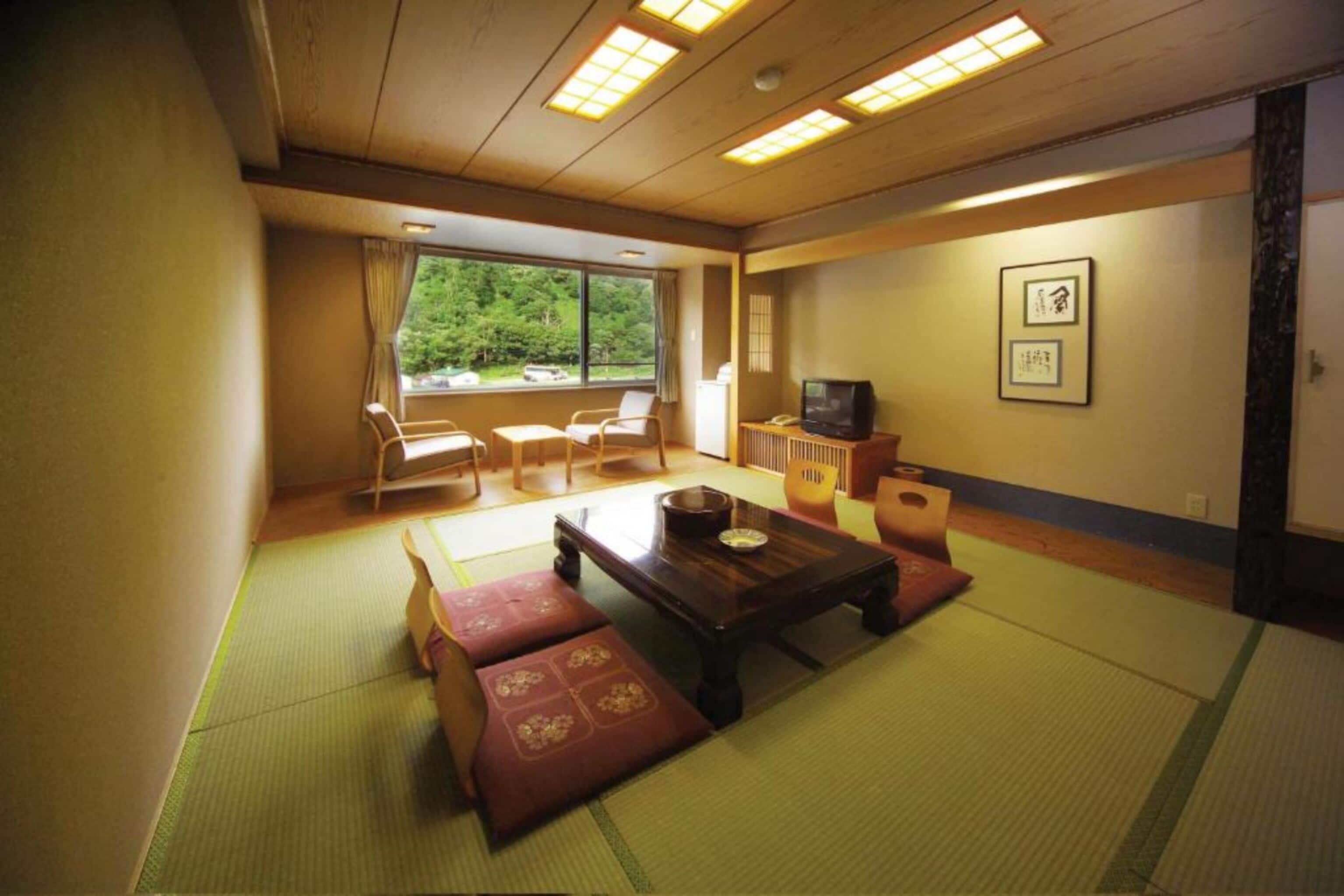 Et traditionelt japansk rum med tatamimåtter, et lavt træbord og et fjernsyn.