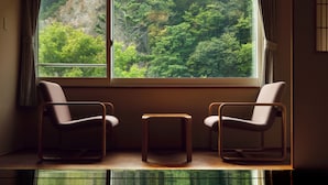A room with two chairs and a small table by a window with a view of trees.