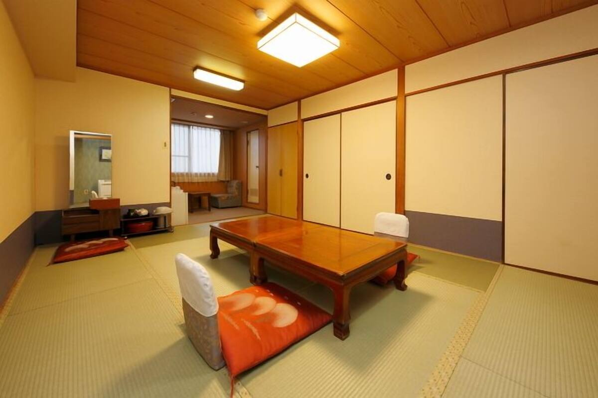 Ein traditioneller japanischer Raum mit Tatami-Boden, einem niedrigen Holztisch und Schiebetüren.