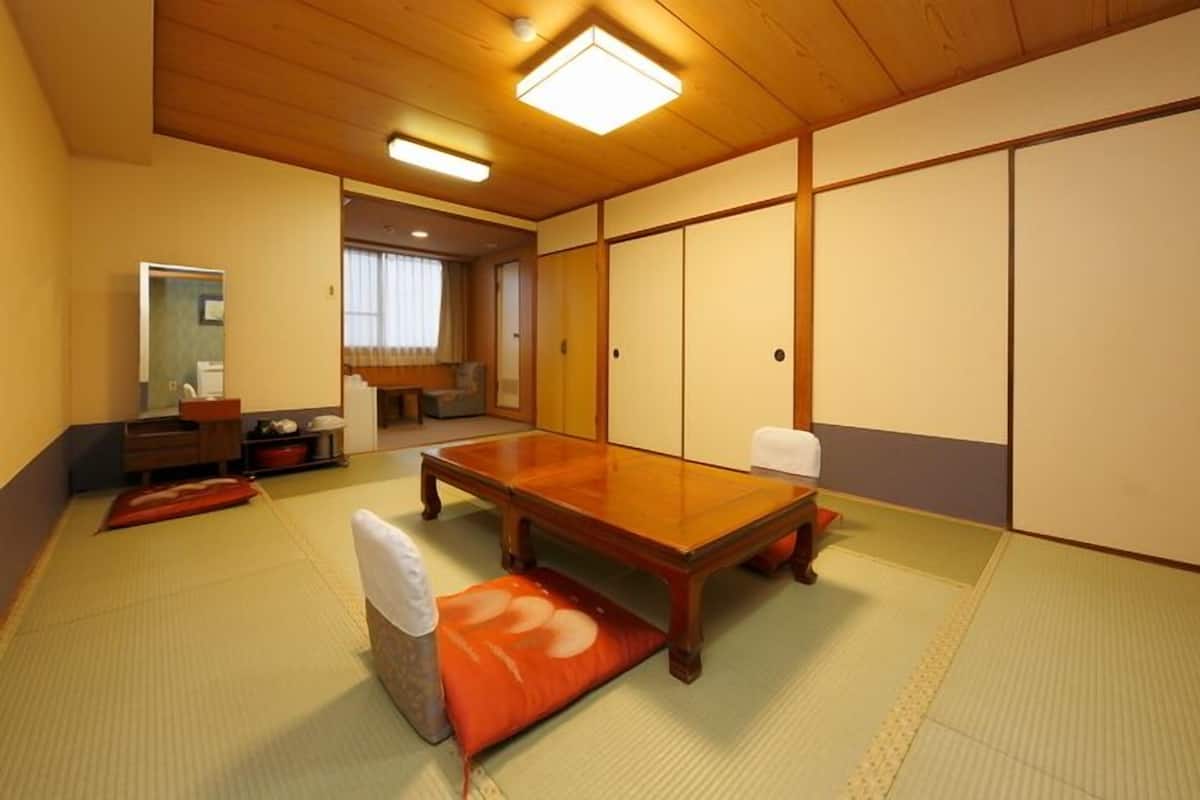 Ett traditionellt japanskt rum med tatamimattor på golvet, ett lågt träbord och skjutdörrar.