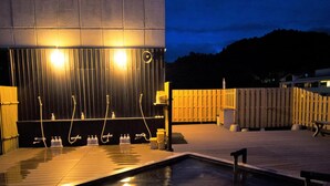 A spa area with a pool, multiple showerheads, and a wooden deck. - Konpira-spa Yumoto Yachiyo (Kotohira)