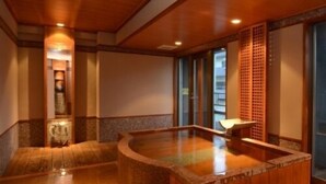 A traditional Japanese onsen with wooden flooring and a central hot spring. - Private spa Hotel Kotone (Kotohira)