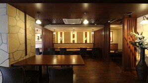 A restaurant with a long wooden table, multiple chairs, and a decorative vase with flowers. - Private spa Hotel Kotone (Kotohira)