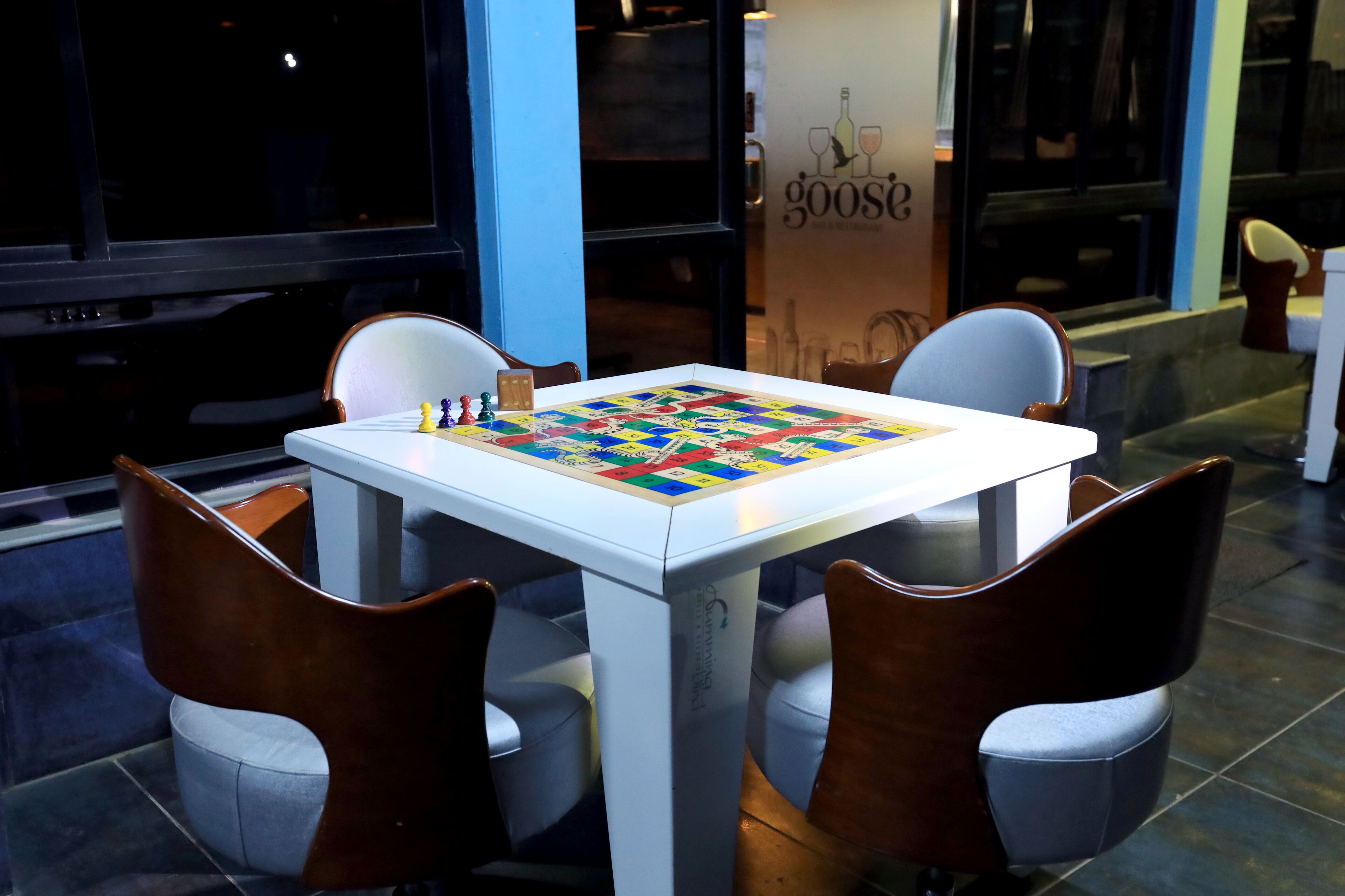 Una mesa con un juego de mesa, cuatro sillas y una pared con un logotipo.