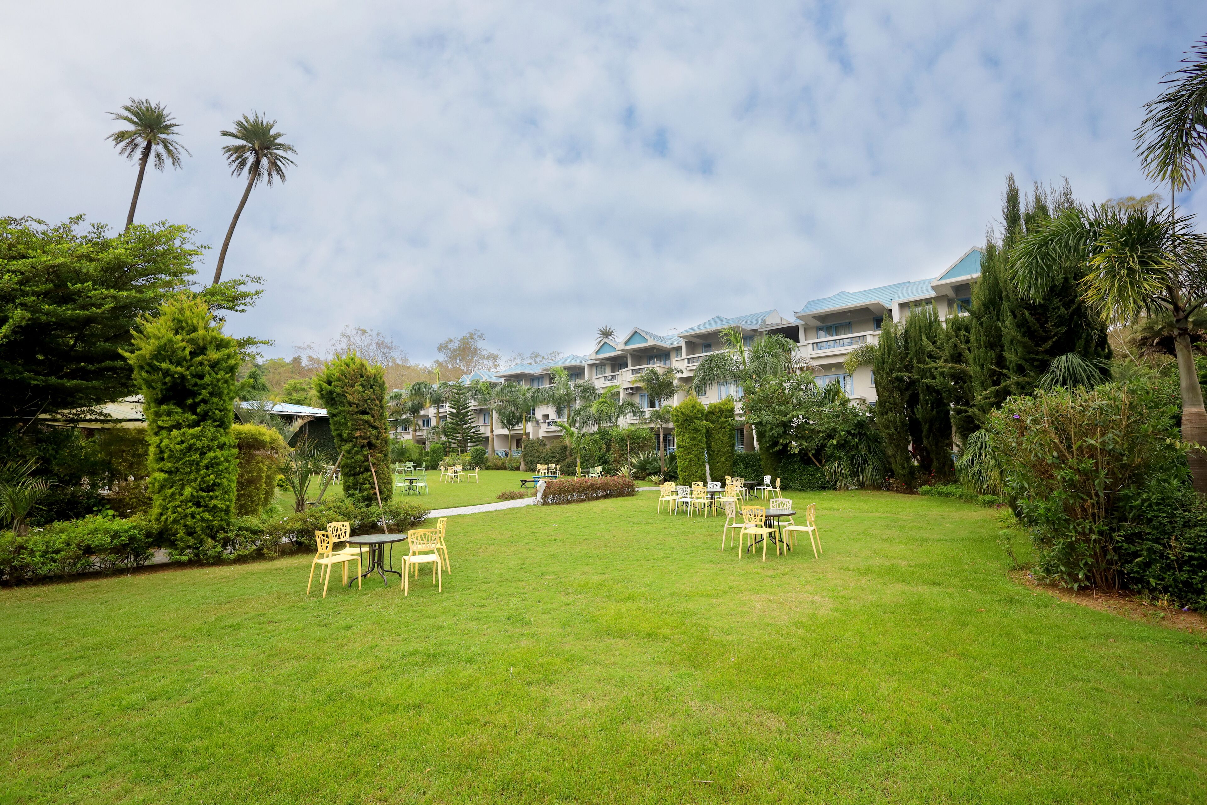 A hotel courtyard with outdoor seating, palm trees, and a building with a blue roof.