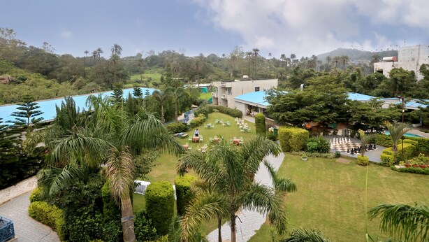 Resort com área de piscina, mobiliário de exterior e vegetação exuberante.