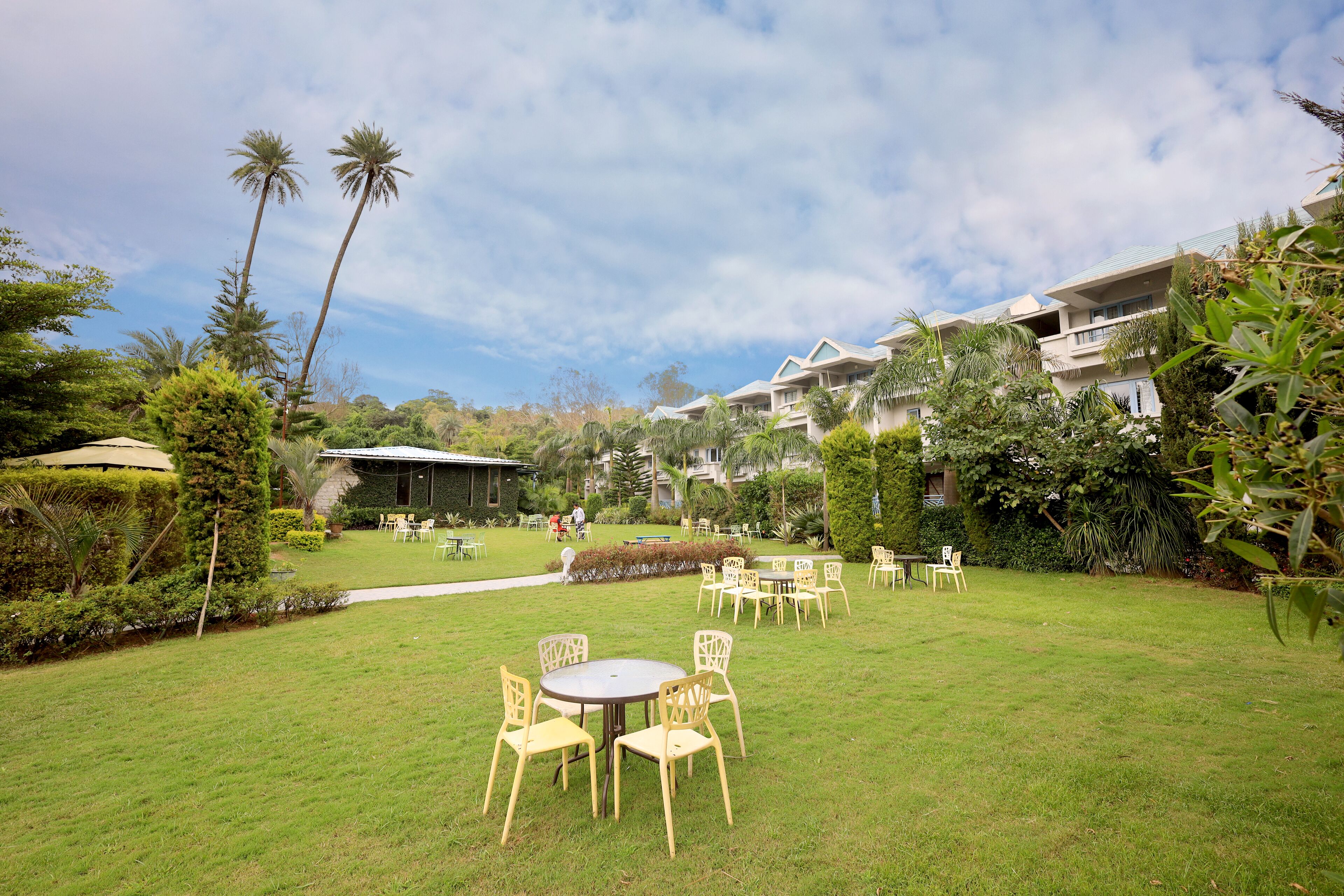 A well-maintained outdoor area with a lawn, several tables and chairs, and a few buildings in the background.