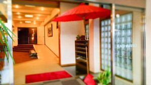 A hotel lobby with a staircase, a red umbrella, and a glass wall with a view. - Beachside Hotel Kashimaso (Tonosho)
