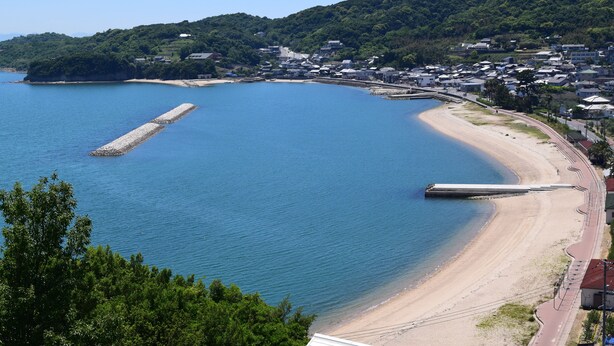 A coastal town with a beach, a pier, and residential buildings. - Beachside Hotel Kashimaso (Tonosho)
