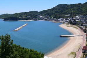 A coastal town with a beach, a pier, and residential buildings. - Beachside Hotel Kashimaso (Tonosho)