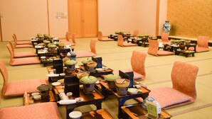 A traditional Japanese room with tatami mats, low tables, and matching chairs. - Beachside Hotel Kashimaso (Tonosho)