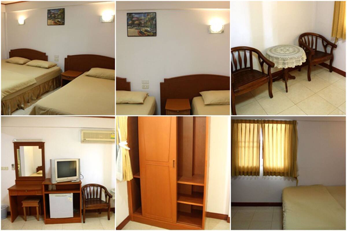 Ein Hotelzimmer mit zwei Betten, einem Schreibtisch mit Fernseher, einem Kleiderschrank und einem kleinen Tisch mit Stühlen.