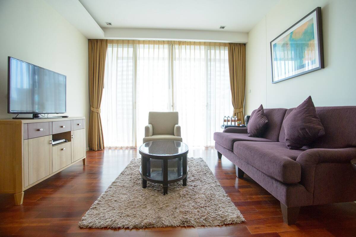 Una sala de estar con un sofá, un sillón, una mesa de centro, un televisor y un cuadro en la pared.