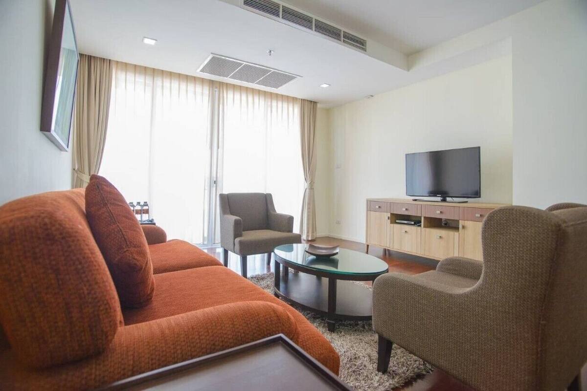 Una sala de estar moderna con un sofá, sillones, una mesita de centro y un televisor de pantalla plana.