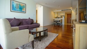 A modern living room with a sofa, armchair, coffee table, and a painting on the wall.