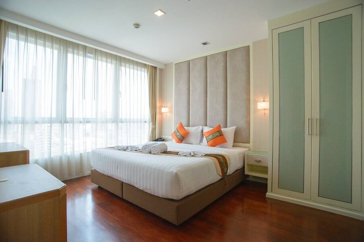 Una habitación de hotel con una cama grande, un escritorio y un armario.