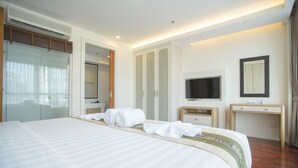 A hotel room with a large bed, a TV, a wardrobe, and a desk.