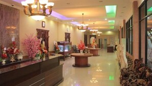 Eine Lobby mit einer Rezeption, mehreren Kronleuchtern und dekorativen Blumenarrangements.