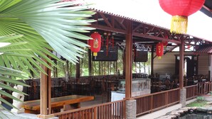 Ein Restaurant im Freien mit Holztischen und -stühlen, einem Steinweg und einem kleinen Teich.