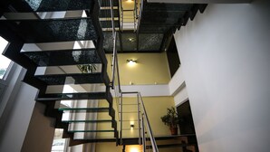A multi-level interior with a staircase, a potted plant, and a wall-mounted light fixture. - Notte Stellata (Savigliano)