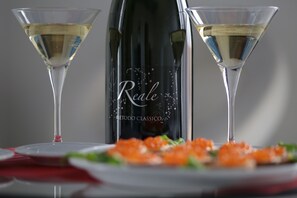 Una botella de vino Reale y dos copas de vino blanco sobre una mesa con un mantel rojo y un plato de huevas de salmón.