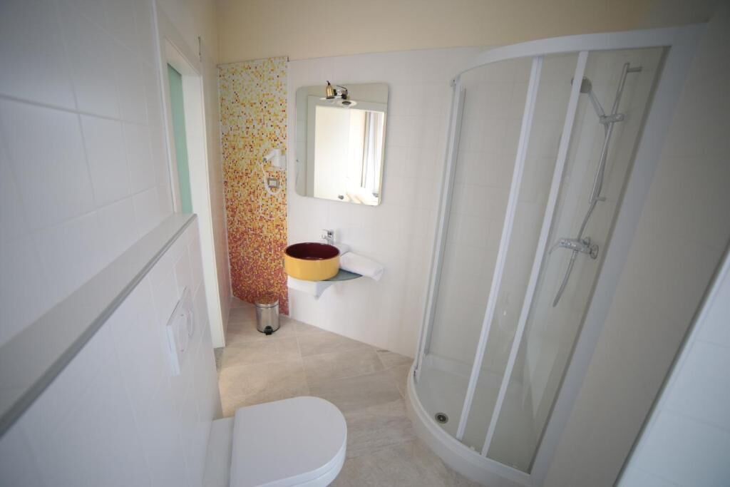 Une salle de bain comprenant des toilettes, un lavabo, une douche et un miroir au-dessus du lavabo.
